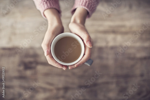 Woman holding coffee cup wooden background