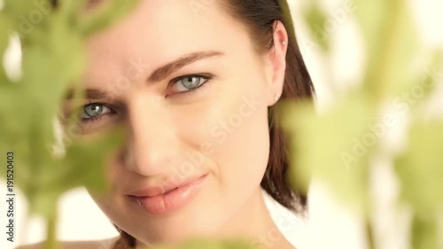 beauty woman with clean face and natural make up smiling looking throung flowers and plants photo