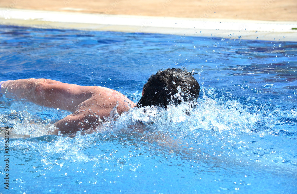 Detail of a Caucasian man swimming crawl stroke in an outdoor pool.