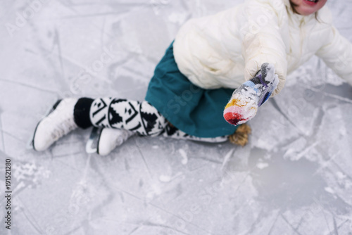 Young girl playing hockey falling over on frozen lake photo