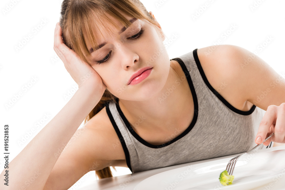 sad slim woman eating piece of broccoli from plate isolated on white sad slim woman eating piece of broccoli from plate isolated on white