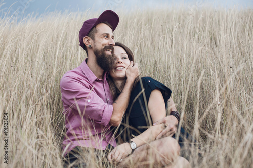 Smiling couple sitting in a field of long grass embracing, Krasnodar, Russia photo