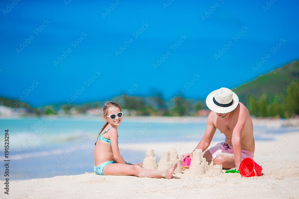 Family making sand castle at tropical white beach. Father and girl playing with sand on tropical beach Family making sand castle at tropical white beach. Father and girl playing with sand on tropical beach