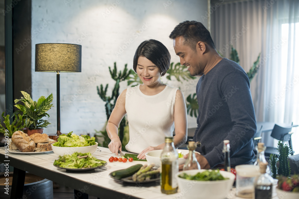 Happy Asian couple preparing food in the kitchen at home. Happy Asian couple preparing food in the kitchen at home.