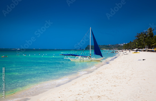 Philippine traditional boat with blue sail on White Beach. Boracay, Philippines.