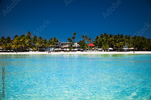 Tropical vacation on white sand beach with sun  blue sky and palm trees. White beach at Boracay  Philippines.
