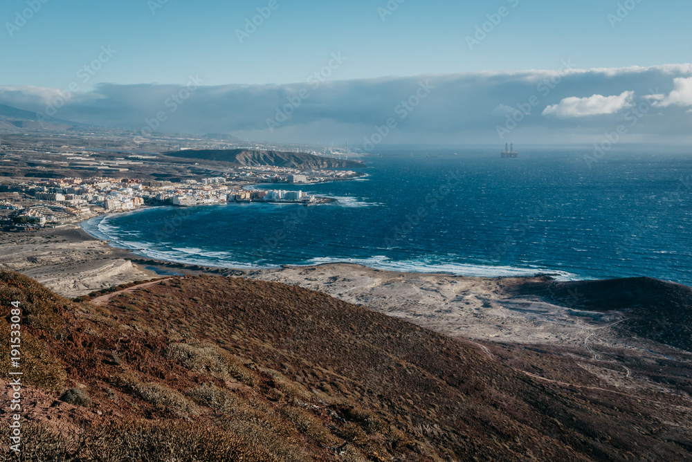 View of the ocean bay with the little town on the shore and the oil platform in the morning