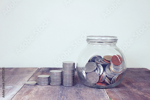 Coins stack shape increase top up and glass bowl collect coins on the wood table , saving concept. photo