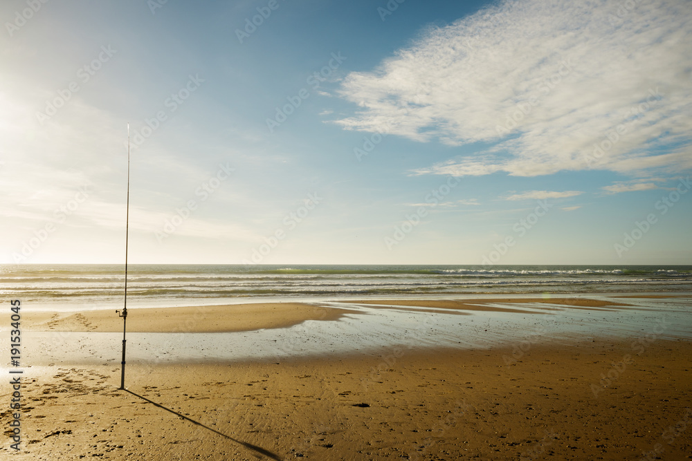 angling with a fishing rod on a deserted beach