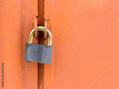 Lock hanging on old red rusty garage door with copy space