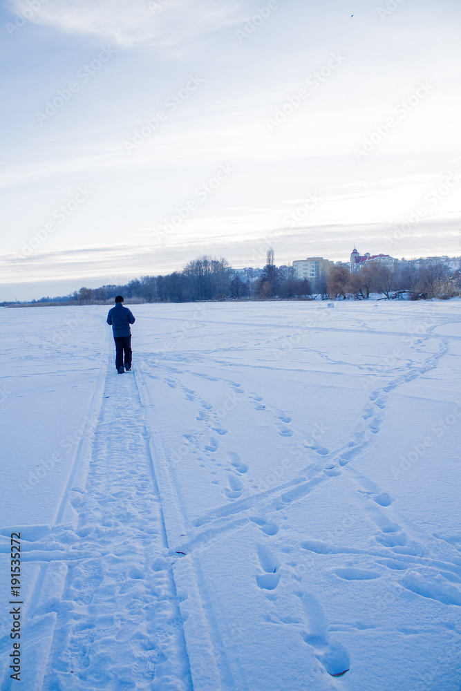 A man in dark clothes, goes into the distance along the path in the snow, on a winter day.