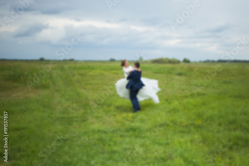 Blurry romantic bride and groom walking at scenic summer landscape outside. Horizontal color photography.