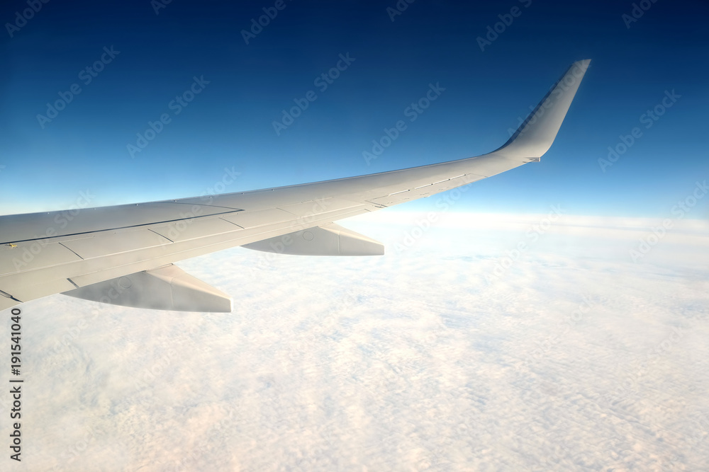 Beautiful top view from passenger supersonic airplane window flying high above white clouds in blue sky Beautiful top view from passenger supersonic airplane window flying high above white clouds in blue sky
