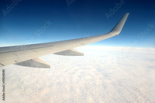 Beautiful top view from passenger supersonic airplane window flying high above white clouds in blue sky