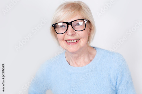 Portrait of a smiling old woman wearing glasses. Beautiful modern grandmother is 70 years old - a pensioner.