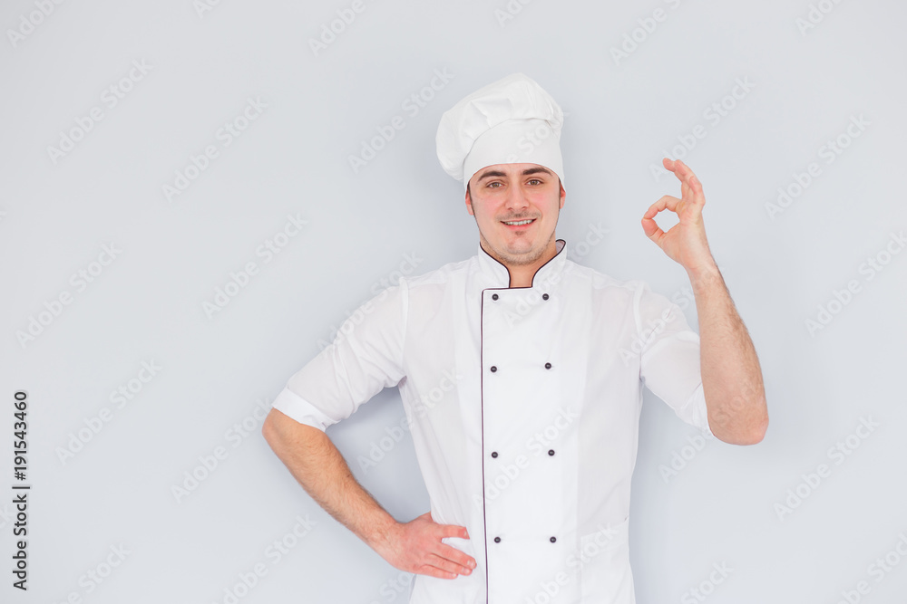 Young chef cook shows ok on a white background Young chef cook shows ok on a white background
