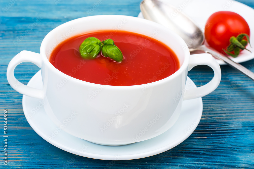 Cream soup of fresh red tomatoes on blue wooden background Cream soup of fresh red tomatoes on blue wooden background