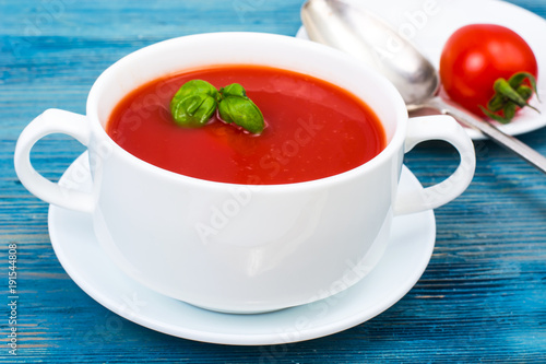 Cream soup of fresh red tomatoes on blue wooden background