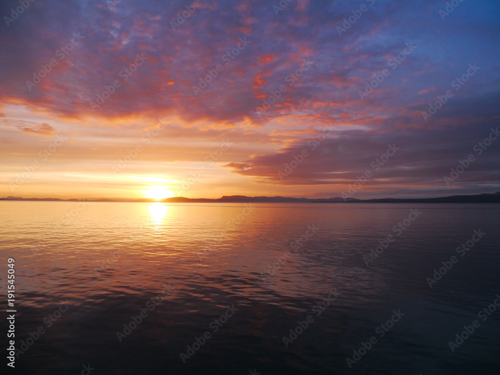 Beautiful pink and orange sunset in Alaska waters - amazing contrast with sunset and clounds