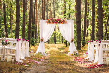 Beautiful romantic festive place made with wooden square and floral roses decorations for outside wedding ceremony in green park. Wedding settings at scenic place. Horizontal color photography.