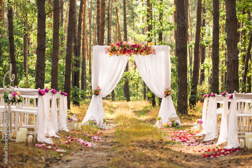 Beautiful romantic festive place made with wooden square and floral roses decorations for outside wedding ceremony in green park. Wedding settings at scenic place. Horizontal color photography. photo