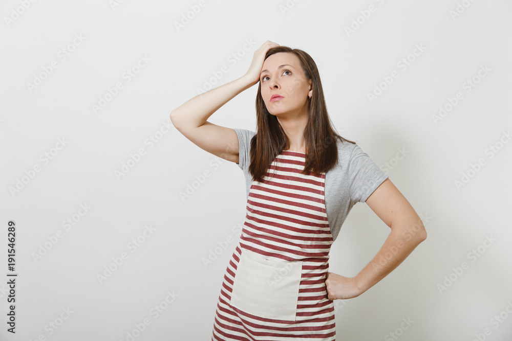 Young attractive sad upset tired brunette caucasian housewife in striped apron isolated on white background. Beautiful housekeeper woman put and touch her hand to head. Copy space for advertisement. Young attractive sad upset tired brunette caucasian housewife in striped apron isolated on white background. Beautiful housekeeper woman put and touch her hand to head. Copy space for advertisement.