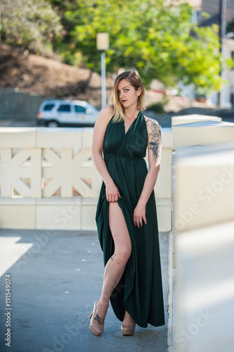 Emerald green halter dress reveals sexy bare leg of beautiful blonde model. © motionshooter