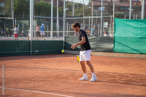 Professional tennis player playing tennis on a clay tennis court on a sunny day.  © pablobenii