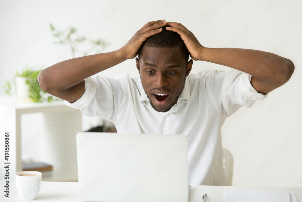 Amazed excited african-american man surprised by unexpected good news win  result online, astonished black businessman looking at laptop screen with  wow face wonders unbelievable fantastic email offer Stock Photo