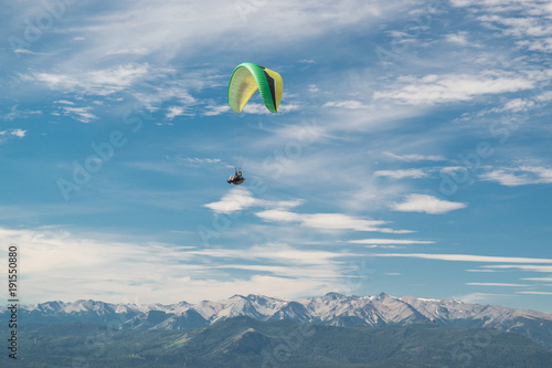 Landscape of a paraglider green color flying high with snowy mountains background