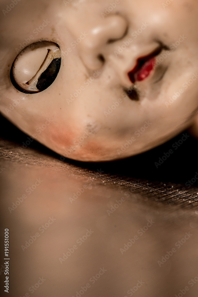 Half face portrait of old doll with eyes closed.