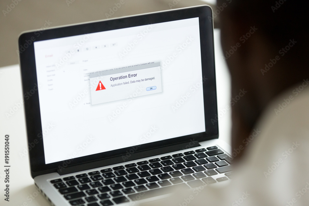 Computer error failure concept, african man using laptop with application failure message on screen, bad software pc app crash, email malware, data loss and recovery, rear view over the shoulder Computer error failure concept, african man using laptop with application failure message on screen, bad software pc app crash, email malware, data loss and recovery, rear view over the shoulder