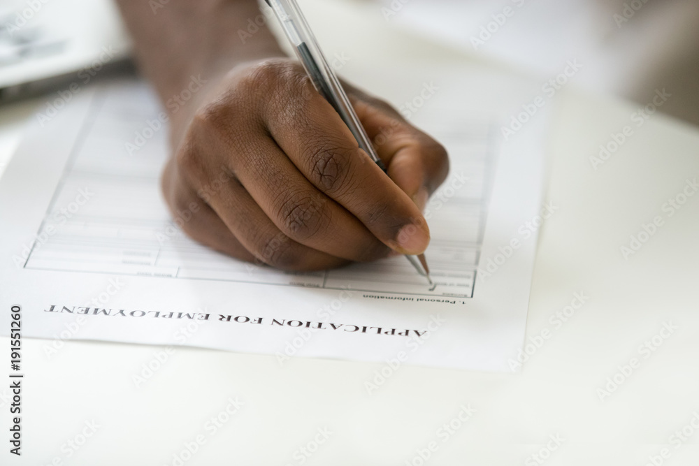 African american man filling employment application, black jobless person applicant writing personal information in form apply for new job, unemployment and work search concept, close up view of hand African american man filling employment application, black jobless person applicant writing personal information in form apply for new job, unemployment and work search concept, close up view of hand