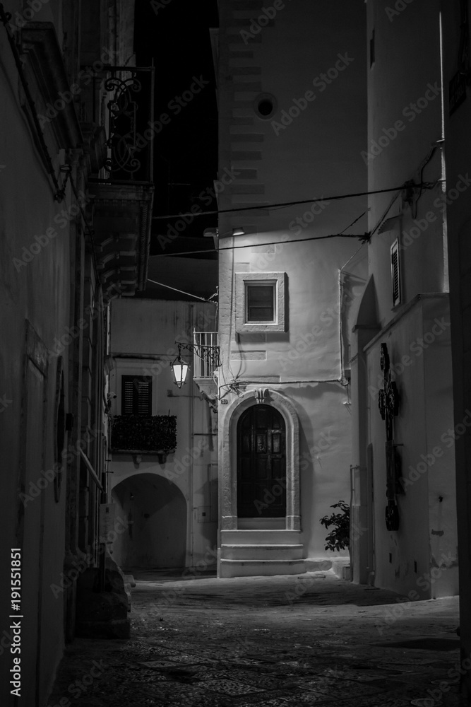 Vertical View in Greyscale of a Street Illuminated By Artificial Light at Night. Martina Franca, South of Italy