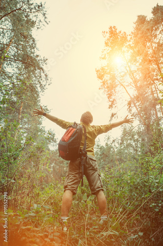 Portrait of a bearded backpacker with rucksack on the forest background