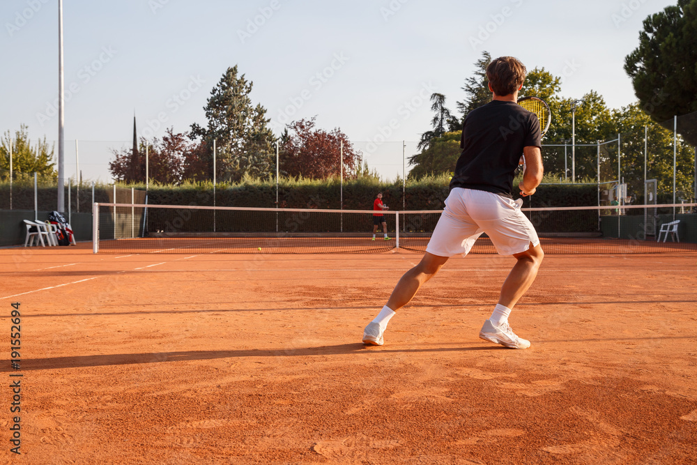 Professional tennis player playing tennis on a clay tennis court on a sunny day. 