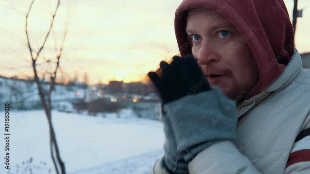 Portrait of a young redbearded man standing frozen against a city