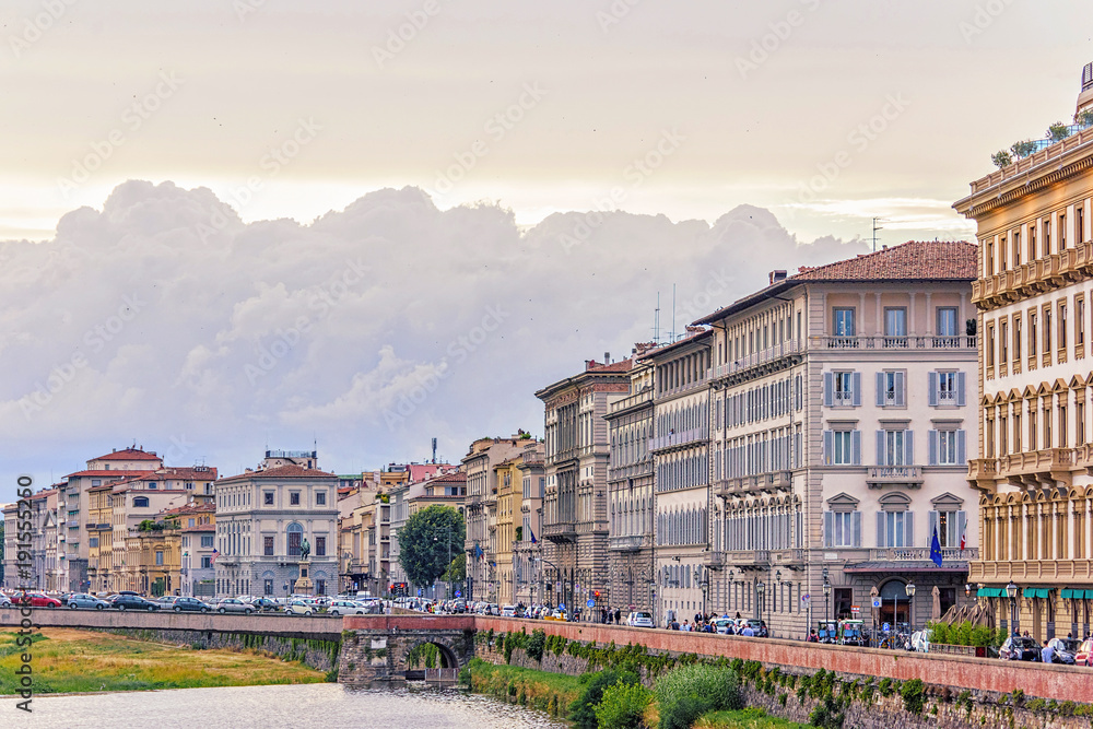 Daylight cloudy day view to Arno river with sunset reflections and cars riding on bridge