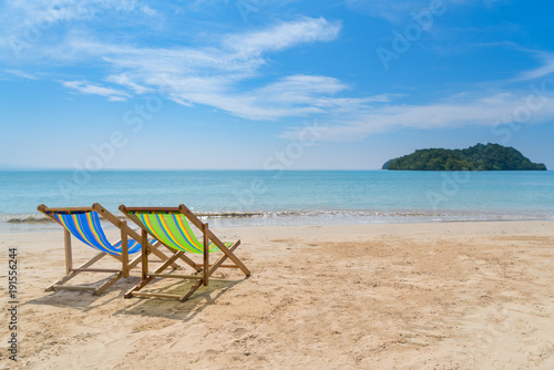 Two beach chairs on the white sand with blue sky and summer sea background. Summer, Vacation, Travel and Holiday concept.