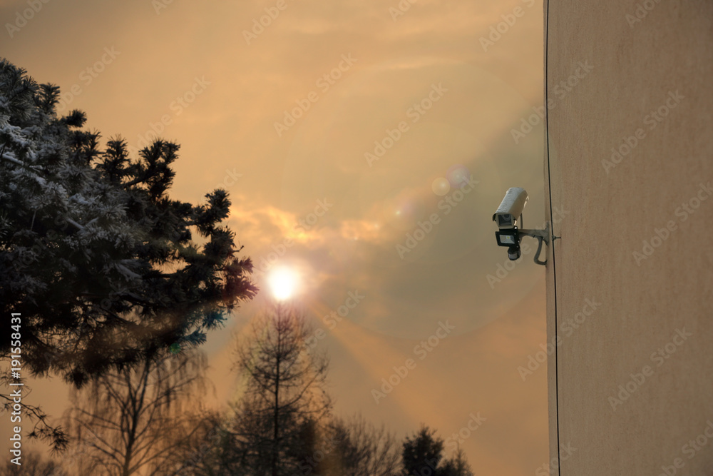 Kamera monitoringu na ścianie budynku, wschód słońca. - obrazy, fototapety, plakaty 