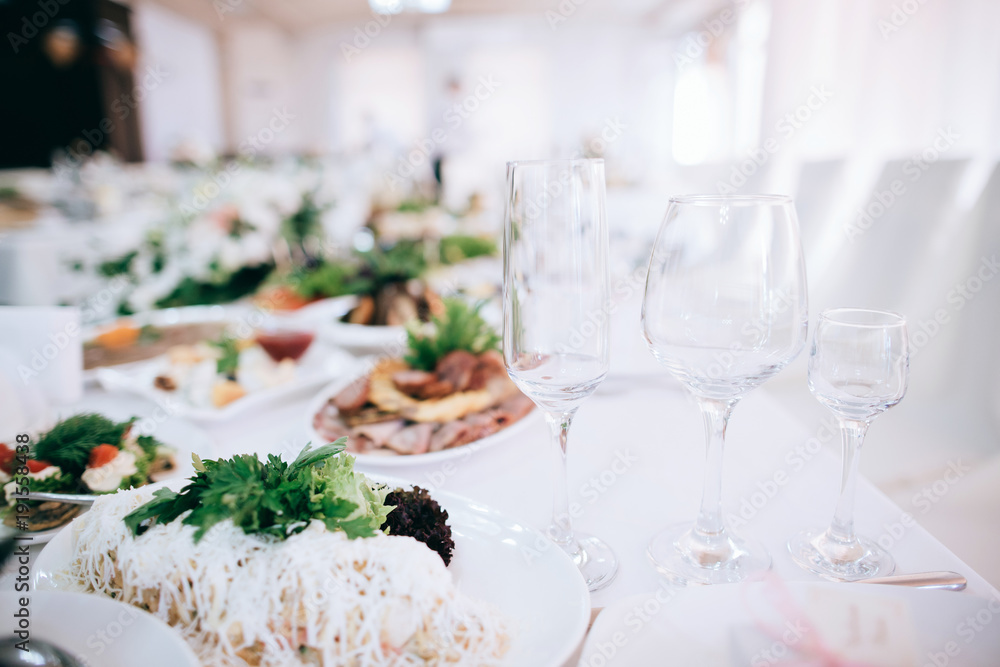 Wedding reception white table arrangement, floral centerpiece decoration, food. Catering service.