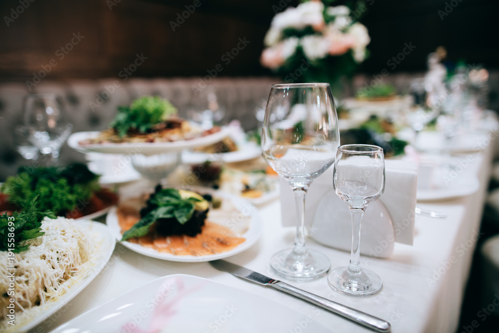 catering table wedding set  with silverware and glass, food and flower decoration