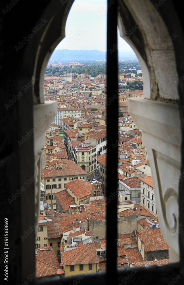 City panorama through the window of the tower, bird's eye view, Florence, Tuscany, Italy; roofs and buildings.