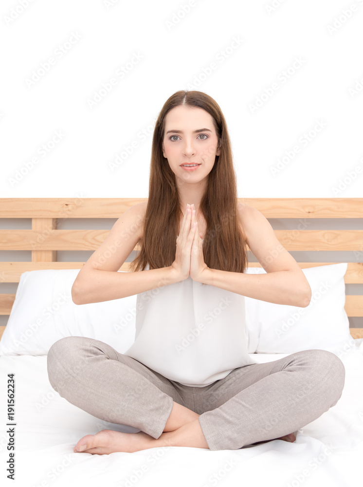 A pretty caucasian young woman practicing yoga, sitting in bedroom, exercise, Lotus pose, namaste, working out,Feeling peace and wellness concept A pretty caucasian young woman practicing yoga, sitting in bedroom, exercise, Lotus pose, namaste, working out,Feeling peace and wellness concept