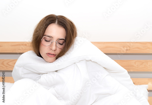 Sick young caucasian woman cold lying in bed, unwell , wrapped in a white blanket feeling ill, has flu and fever. health care and medical concept © kittipong