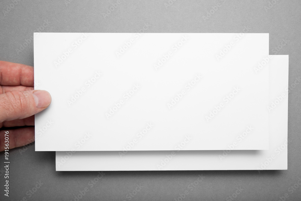 Greeting card in hand on gray background, mock up. Greeting card in hand on gray background, mock up.