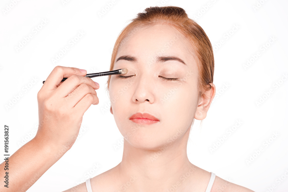 Closed up of face Young caucasian beautiful girl with hand applying make-up by make-up artist,isolated on white ,copy space Closed up of face Young caucasian beautiful girl with hand applying make-up by make-up artist,isolated on white ,copy space