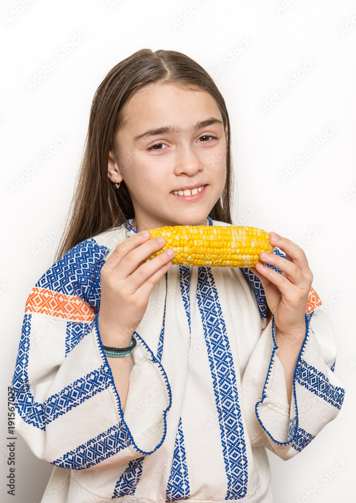 Indoor close up portrait of a smiling young girl getting ready to eat a corn cob. Indoor close up portrait of a smiling young girl getting ready to eat a corn cob.