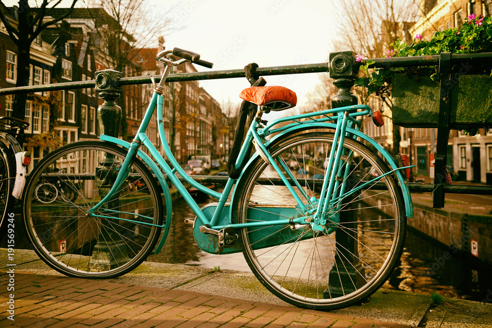 Beautiful vingage photo of a Dutch bicycle on a bridge in Amsterdam with buildings in the background and space for text.