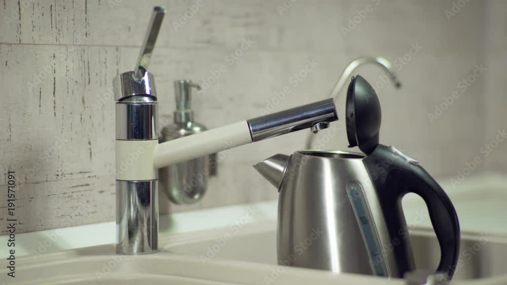 Pouring Water From The Tap Into An Electric Kettle Pouring Water From The Tap Into An Electric Kettle